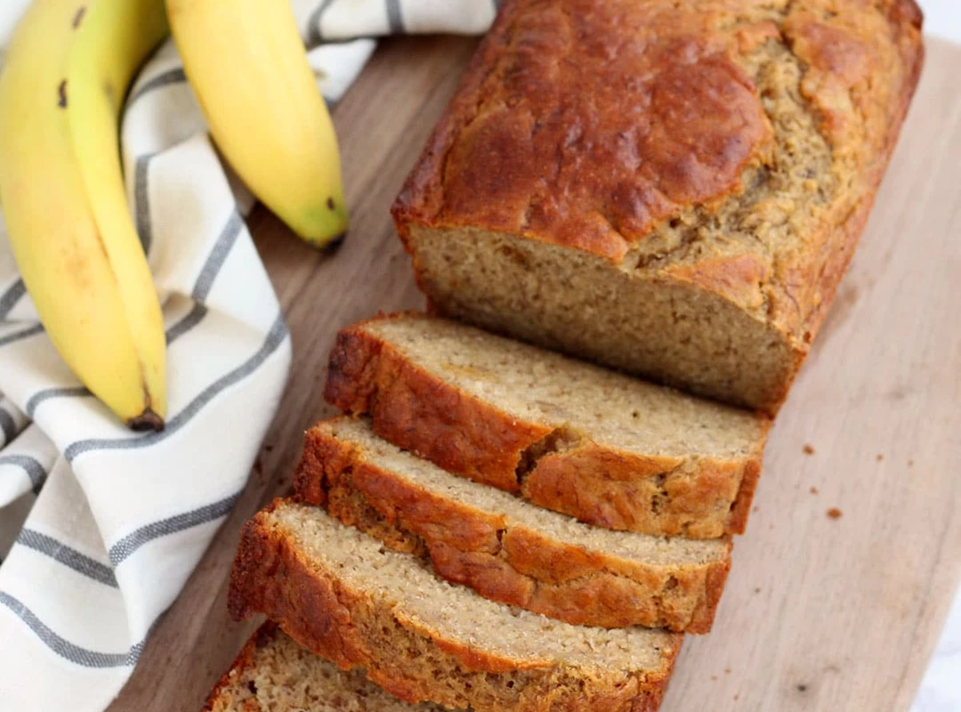 Banana Bread sliced with yellow babanas next to it
